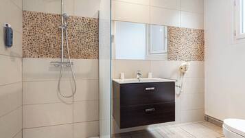 Un baño moderno con ducha, tocador con espejo y retrete.