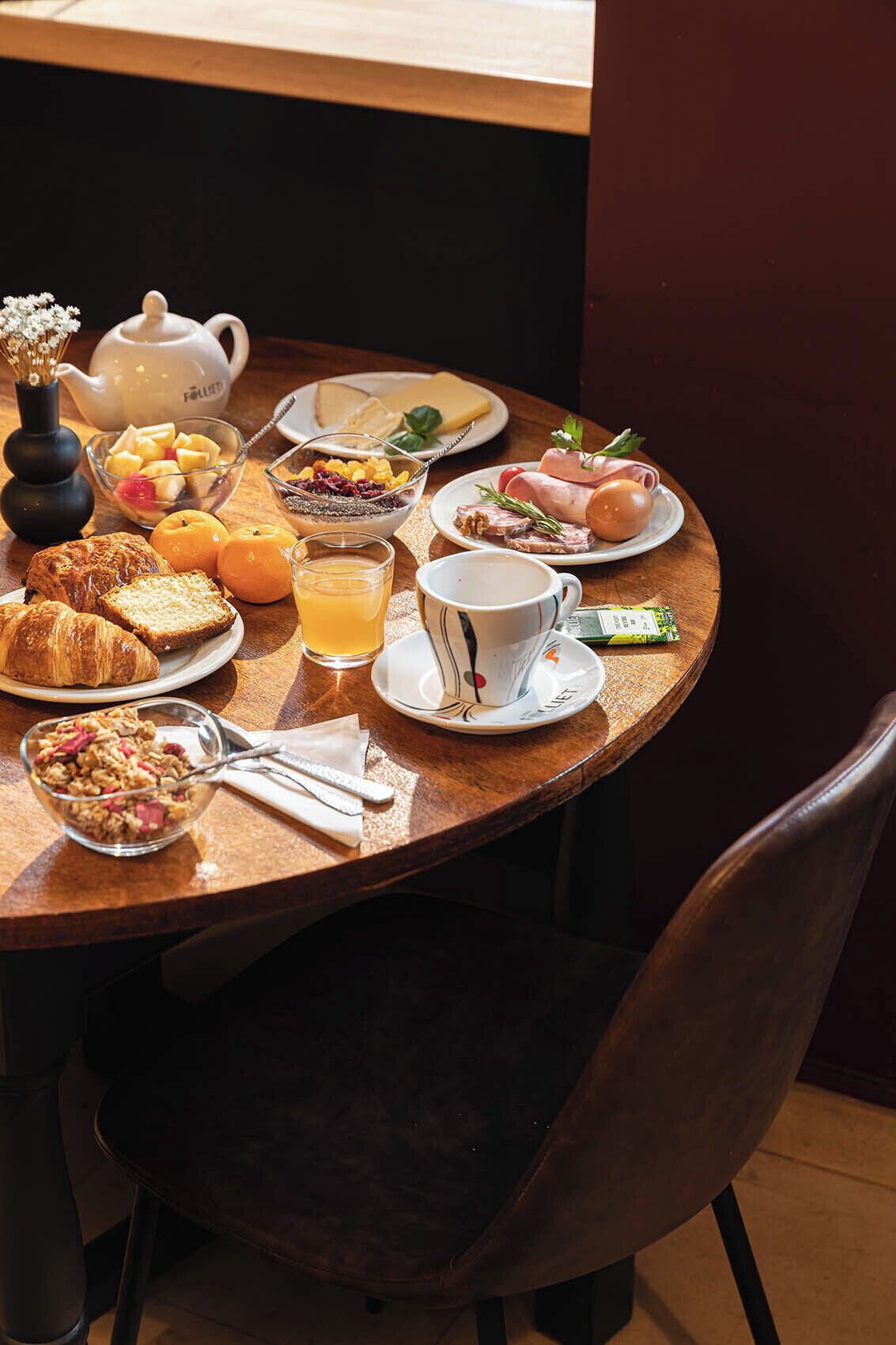 Una mesa de desayuno con una variedad de alimentos, como frutas, pasteles y una tetera.