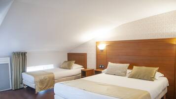Habitación de hotel con dos camas, cabeceros de madera y un ventanal con cortinas.