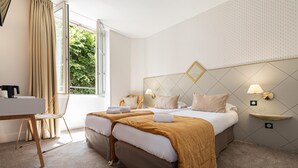 A hotel room with a bed, two bedside tables, a desk, and a chair.