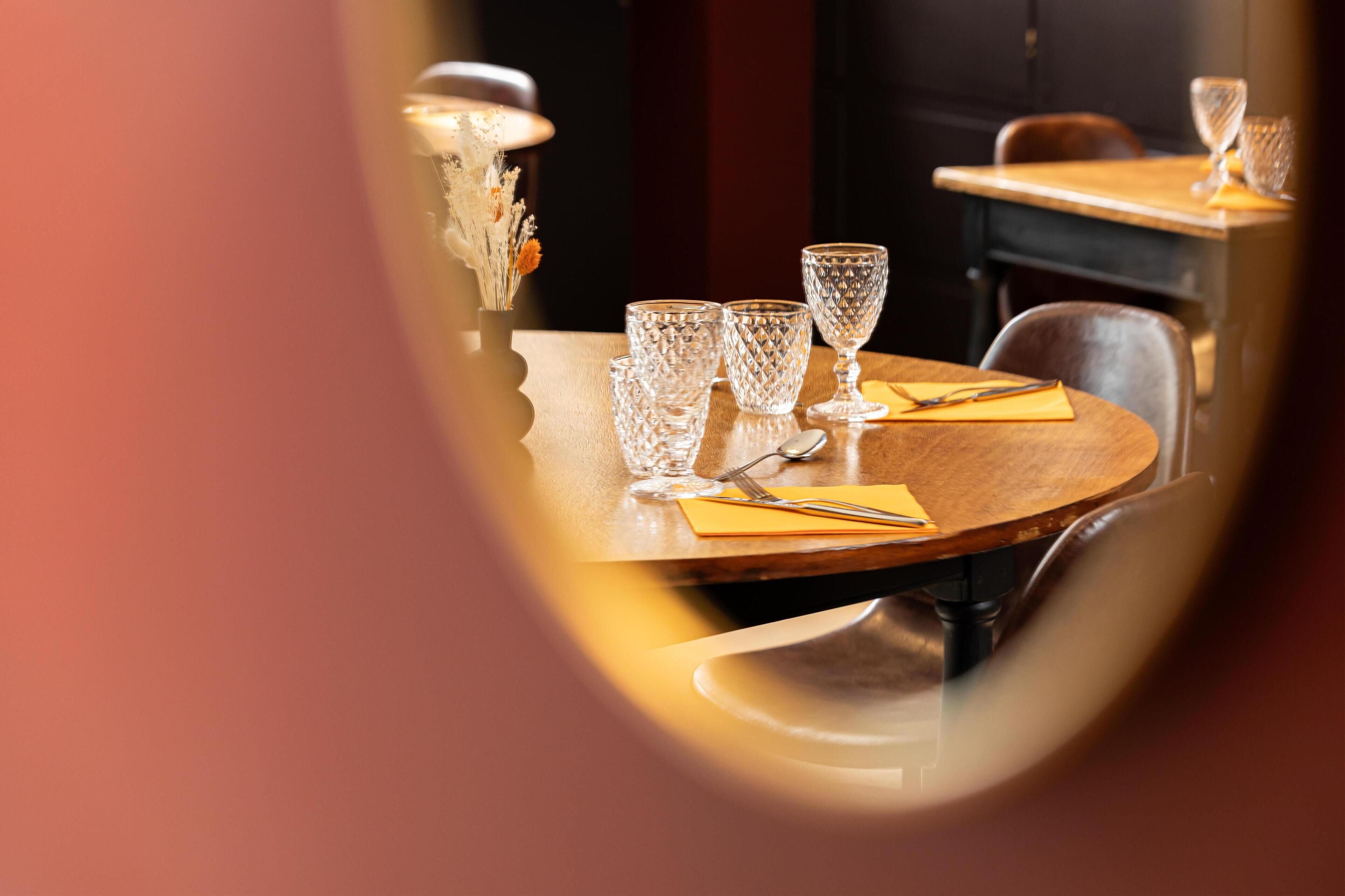 Een eettafel met helder glaswerk en een gele servet, die een warm interieur weerkaatst.