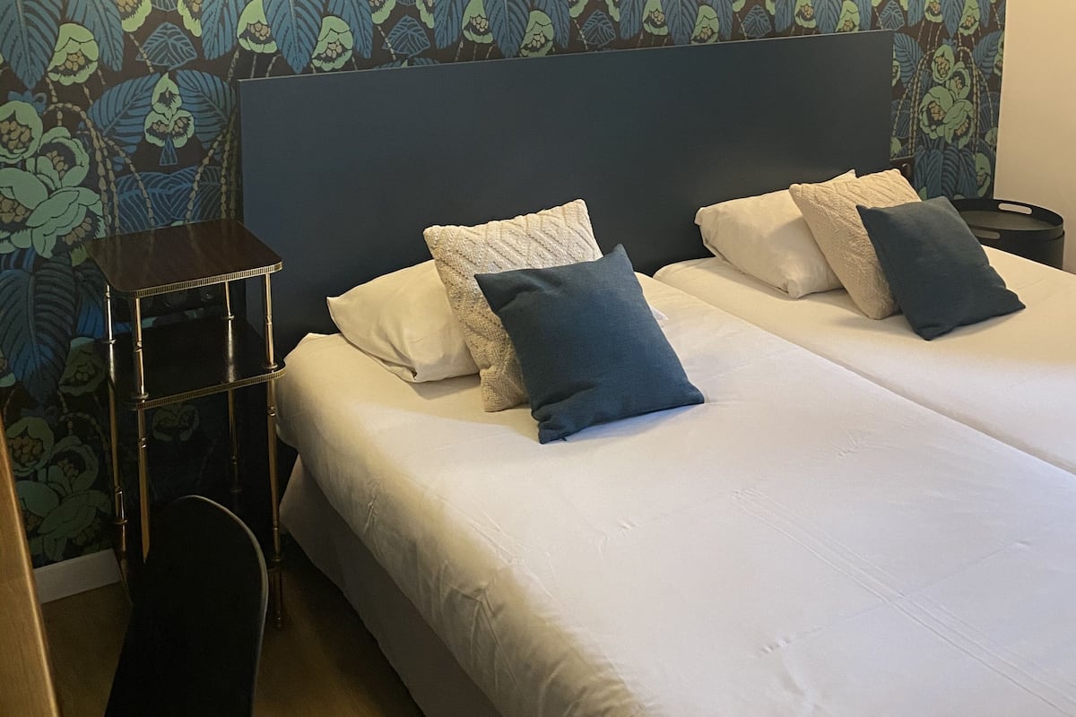 A hotel room with a large bed, two bedside tables, and a wall with a leafy pattern.
