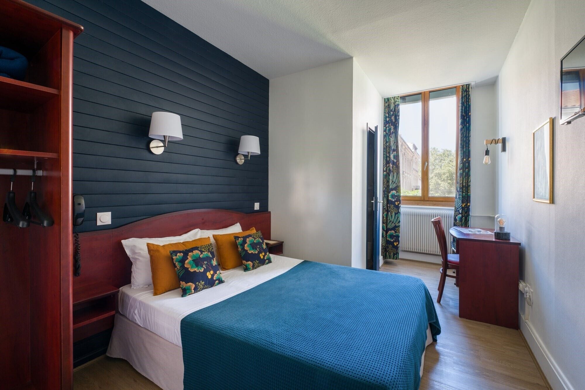 A bedroom with a bed, a desk, and a wardrobe.