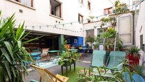 A courtyard with outdoor seating, potted plants, and string lights. - Grand Hotel de la Poste (Vienne)