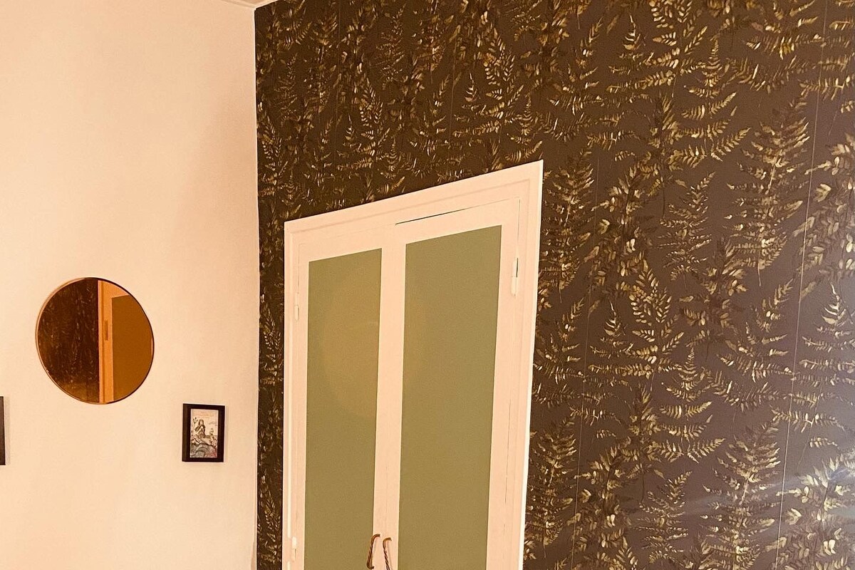 A bedroom with a bed, a bedside table, a mirror, a wardrobe, and a patterned rug.