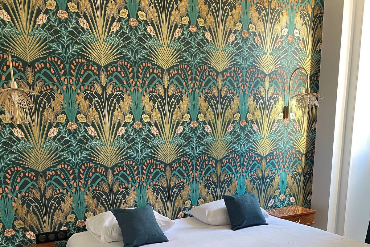 A hotel room with a large bed, two bedside tables, and a wall with a floral wallpaper pattern.