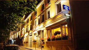 A hotel facade at night with illuminated windows, a visible signboard, and a parked car on the street. - Grand Hotel de la Poste (Vienne)