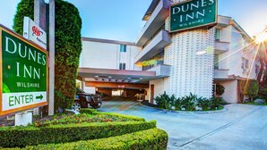 A Dunes Inn Wilshire building with a prominent sign, a parking area, and a well-maintained entrance.