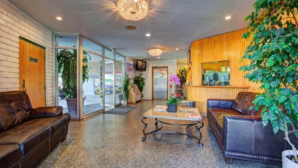 A lobby with leather sofas, a coffee table, and a chandelier.