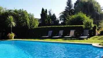 Une piscine à l’eau d’un bleu cristallin, entourée d’une pelouse bien entretenue et de plusieurs chaises longues.
