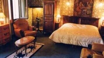 A cozy bedroom with a large bed, a wooden dresser, a chair, and a small table.