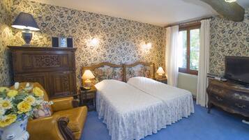 A bedroom with two beds, a dresser, a TV, and a window with curtains.