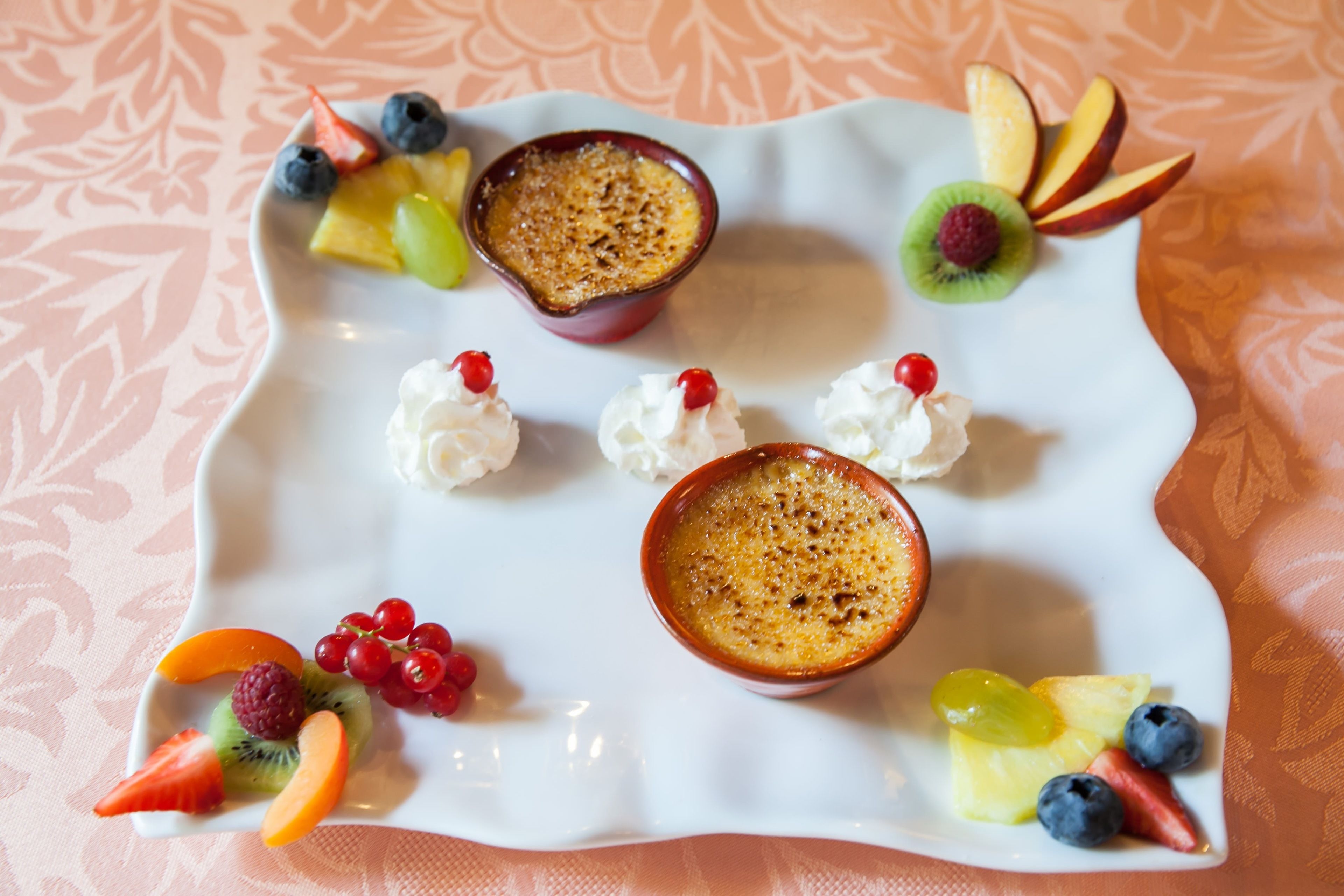 Un plato de postre con diversas frutas y crema batida.