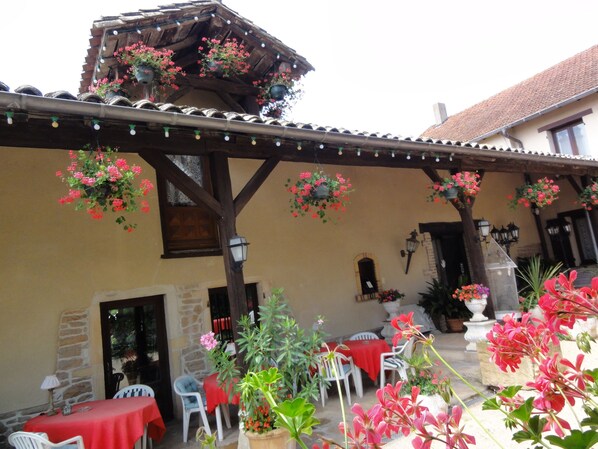 A courtyard with outdoor seating, hanging flower baskets, and a stone wall.