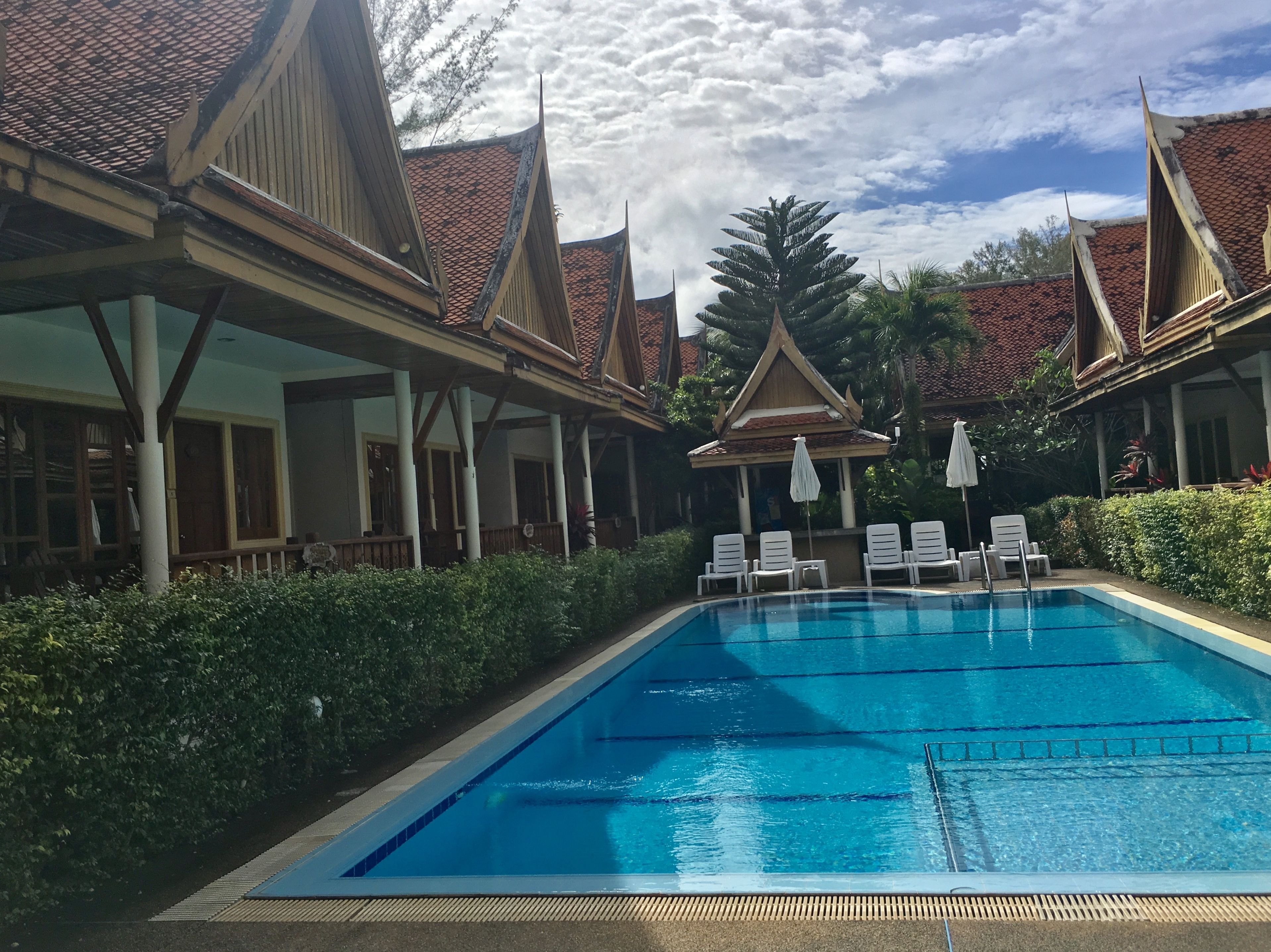 A swimming pool with lounge chairs and a covered area with traditional architecture.