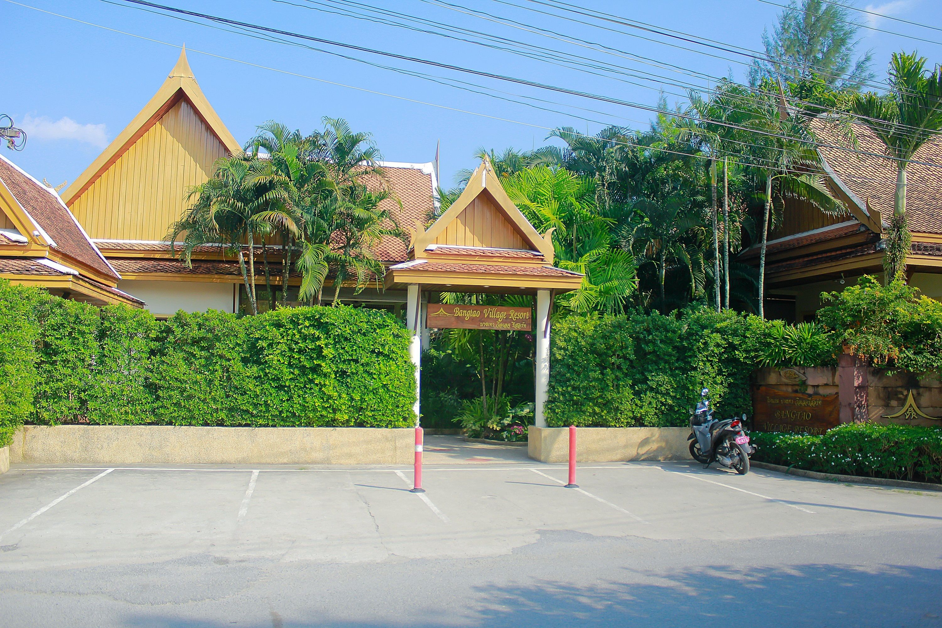 A traditional Thai building with a distinct triangular roof and a sign indicating a resort.