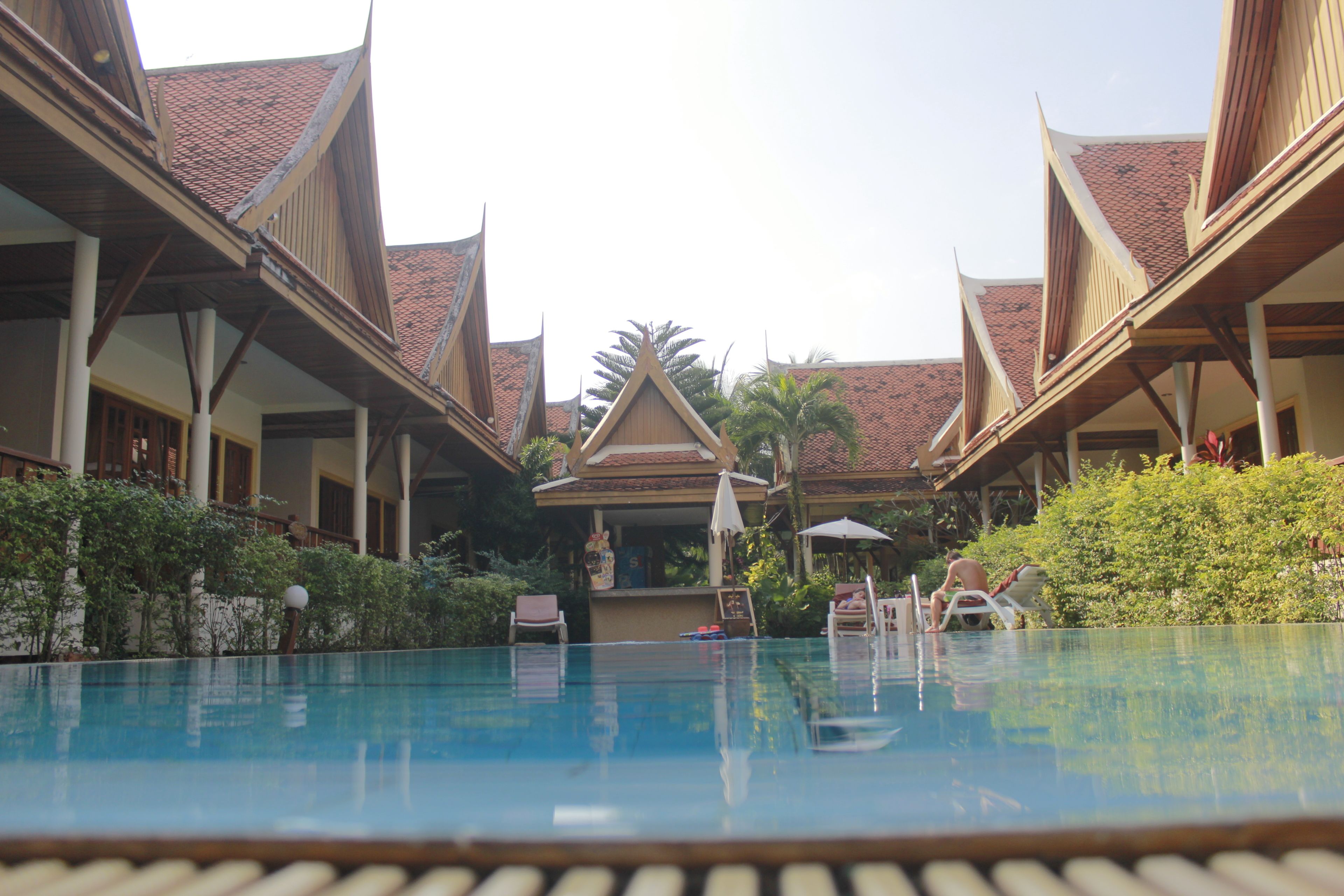 A pool area with a traditional architectural style, including wooden structures and a tiled roof.