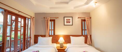 A hotel room with two beds, a nightstand with a lamp, a framed picture on the wall, and a window with curtains.