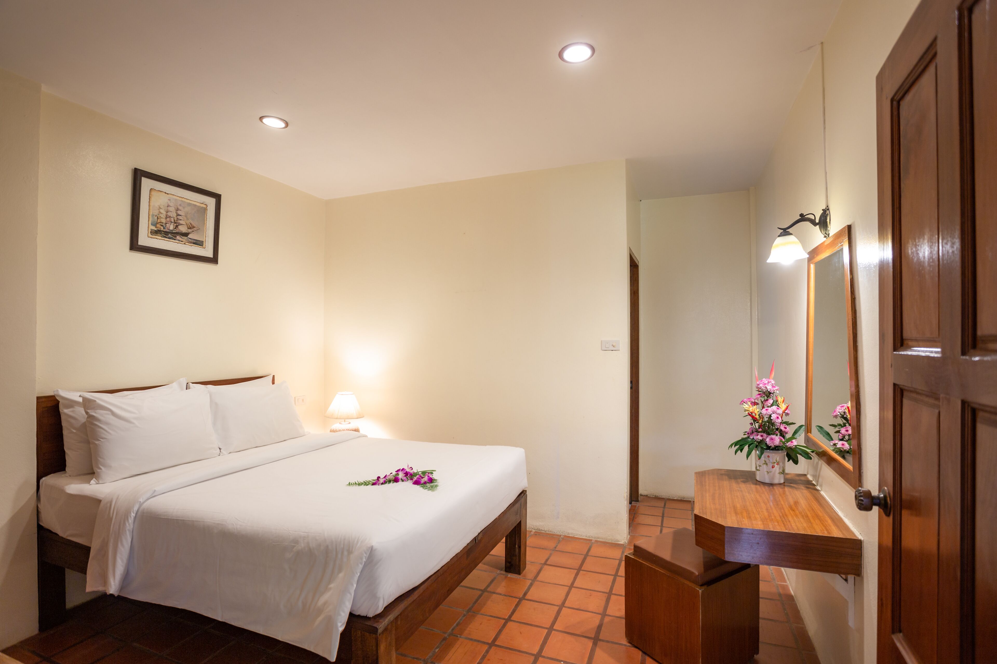 Quarto de hotel com cama, mesa de cabeceira e espelho.