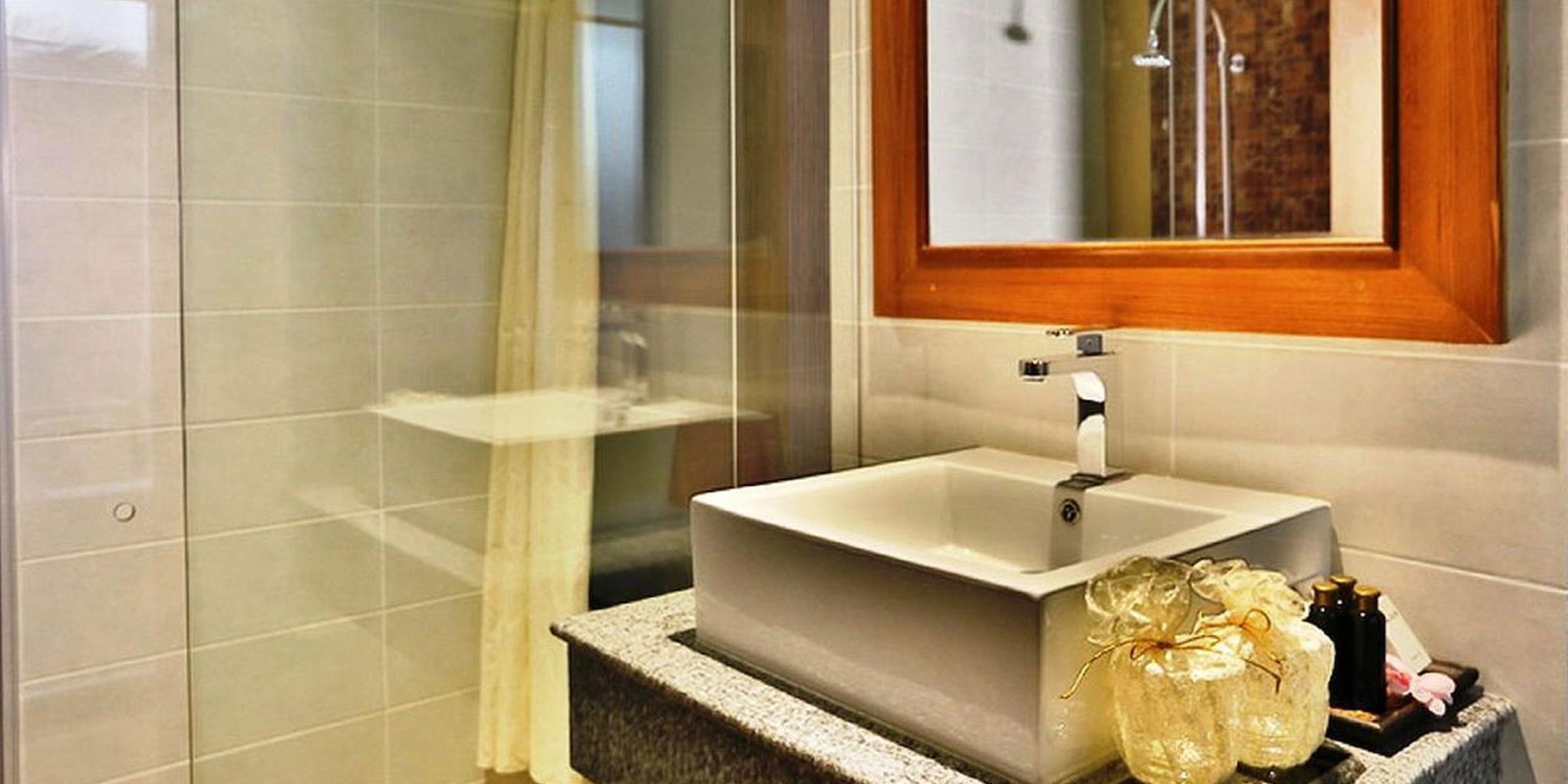 Un baño con un lavamanos blanco, un espejo y una zona de ducha.