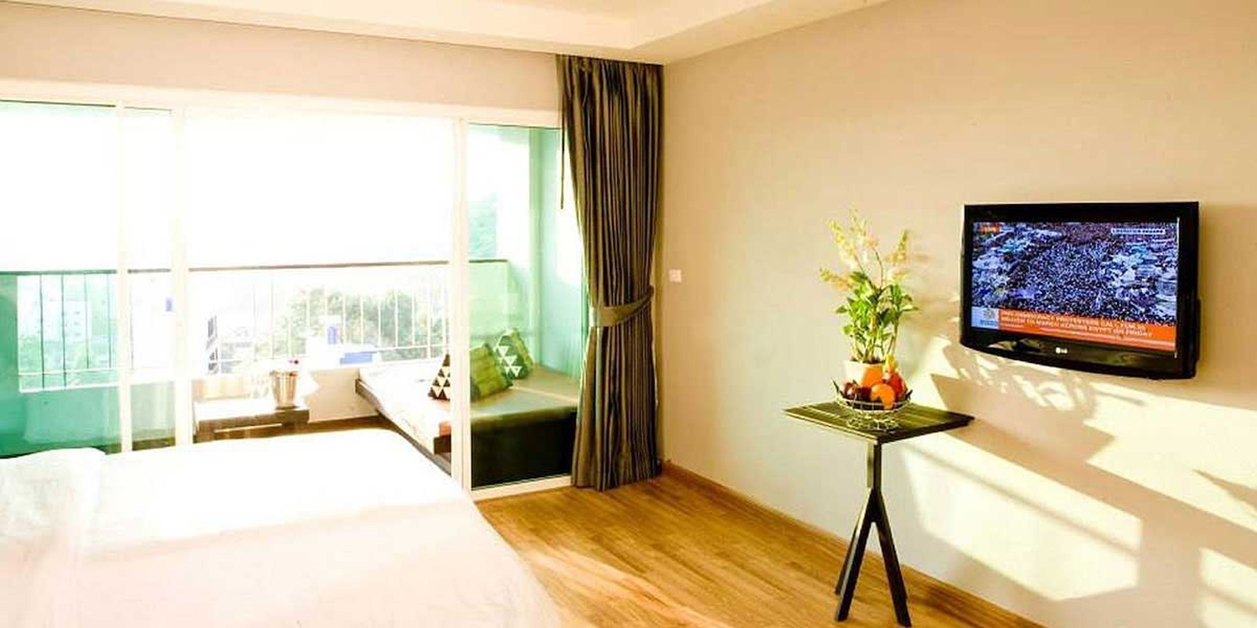 Une chambre d’hôtel avec un lit, une télévision, une petite table avec une plante et une vue sur l’extérieur.