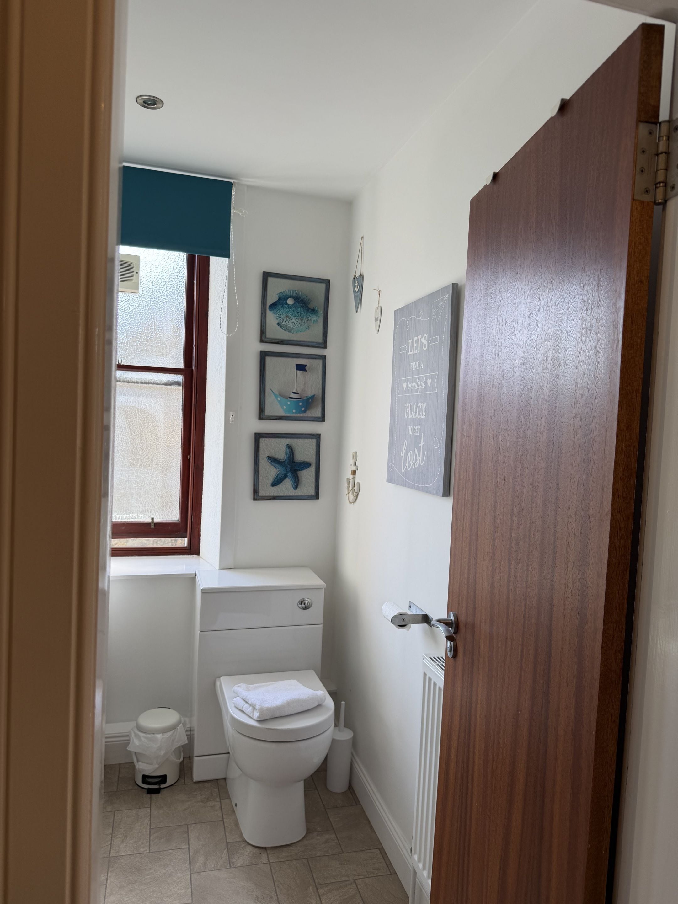 A small, clean bathroom with a toilet, a bidet, a trash bin, and a window.
