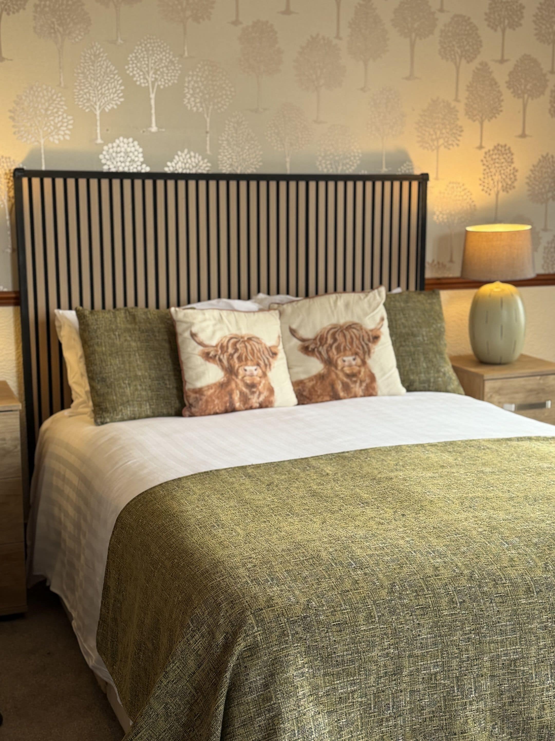 A bed with a headboard, pillows, and a bedside table with a lamp.