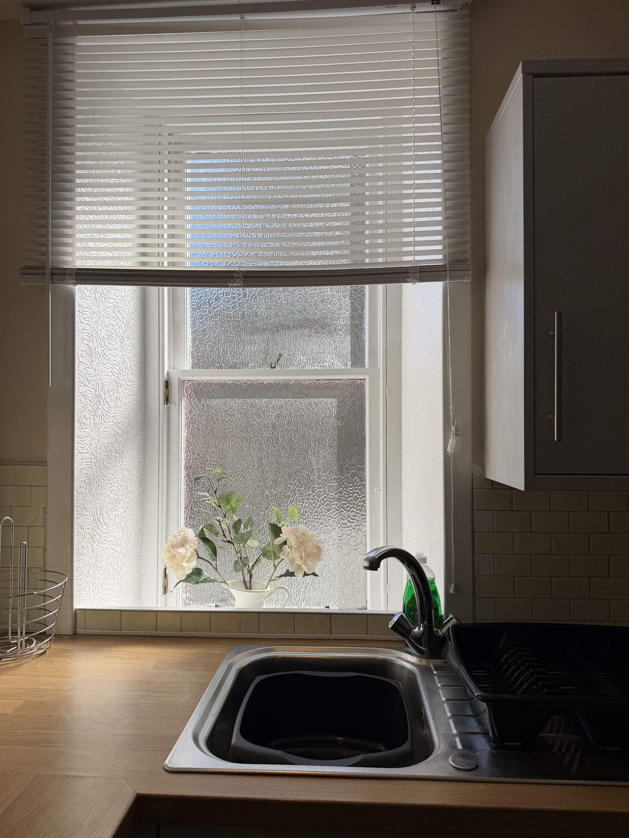 A kitchen with a window, a sink, and a cabinet.