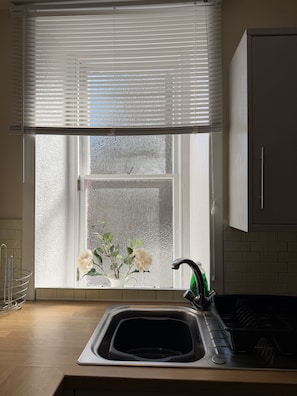 A kitchen with a window, a sink, and a cabinet.