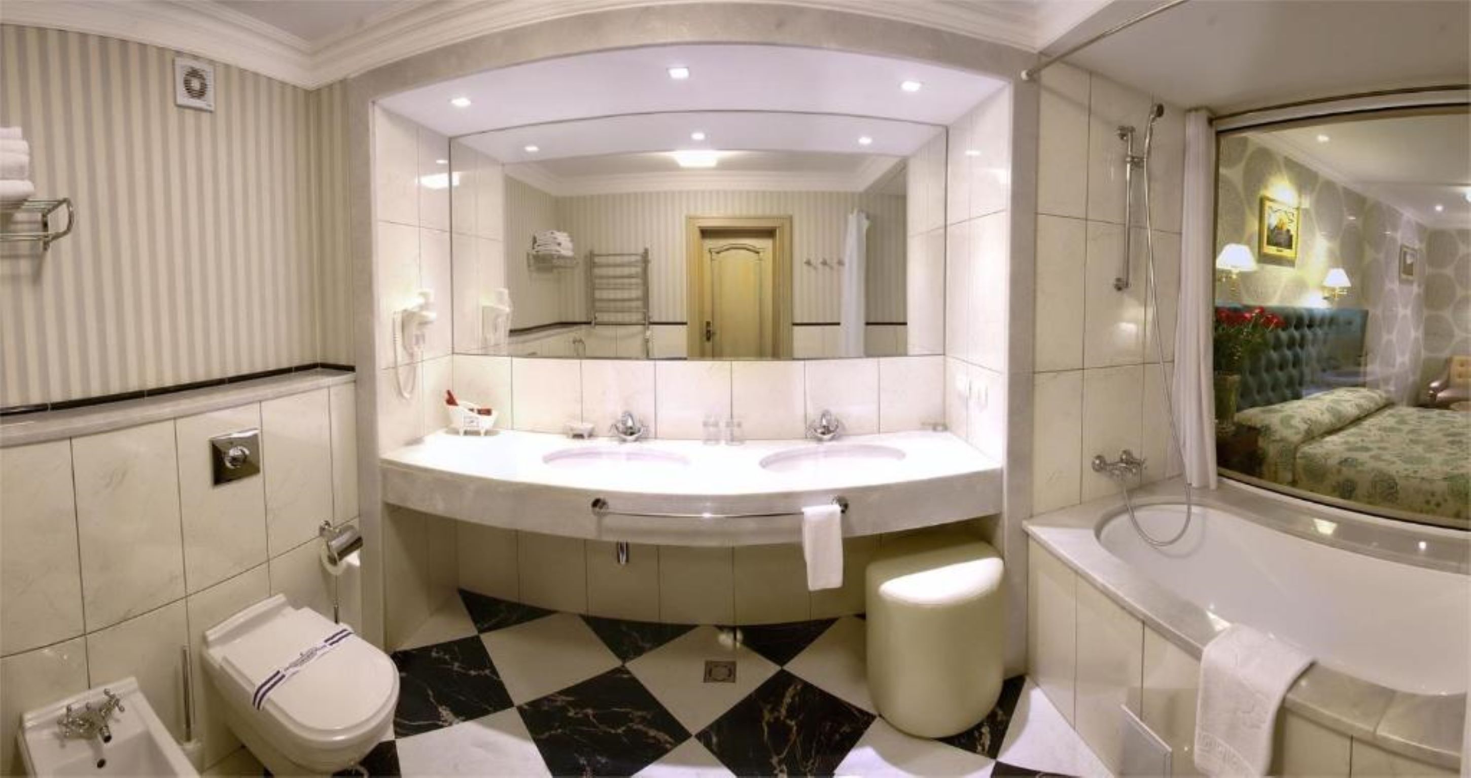 Un baño lujoso con un espejo grande, dos lavamanos, una bañera y un inodoro.