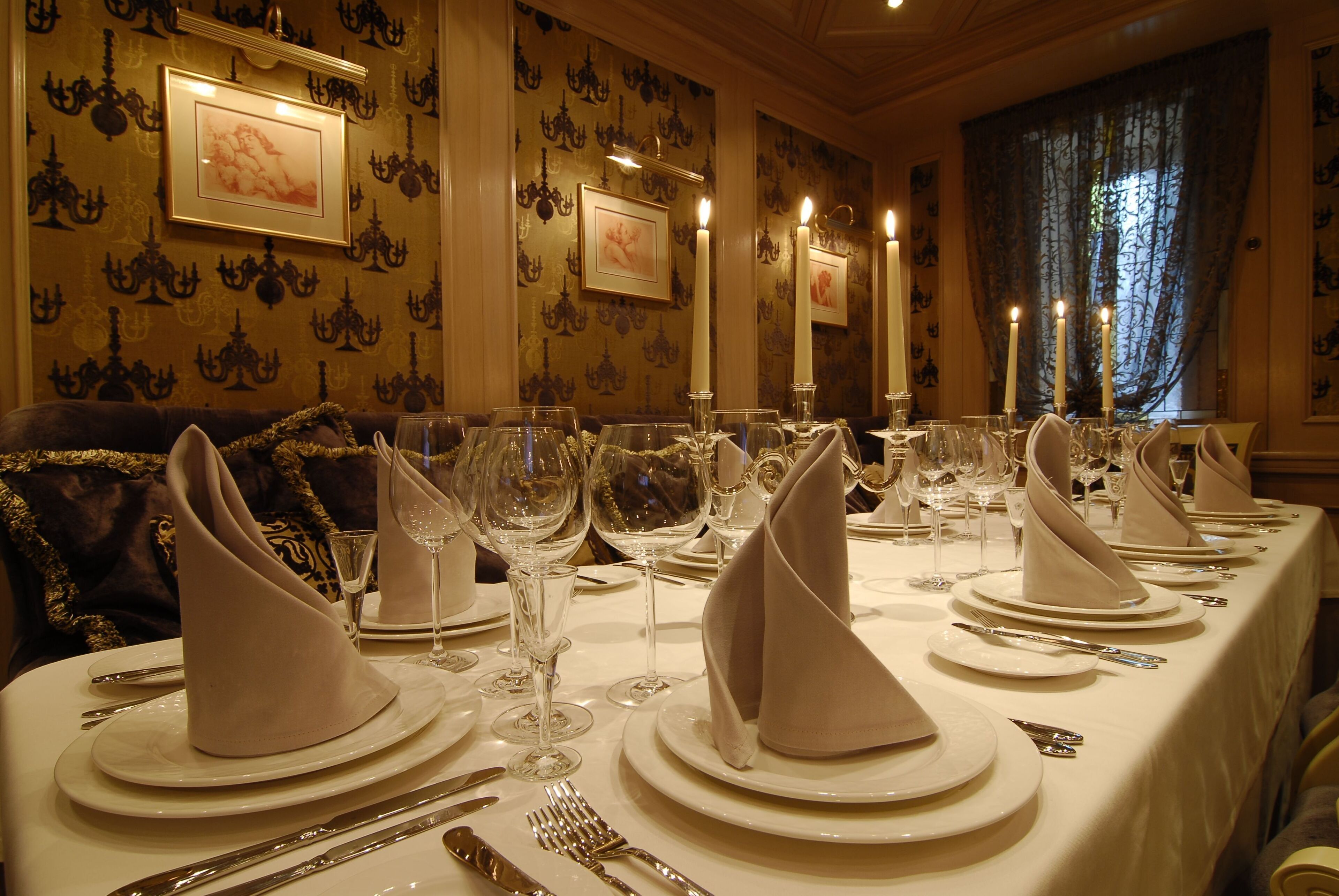 A formal dining table set with multiple place settings, including plates, cutlery, and glasses.