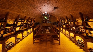 Una bodega subterránea con estanterías de madera y una larga mesa en el centro.