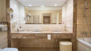 Ein modernes Badezimmer mit zwei Waschbecken, einer Toilette, einer Badewanne und einer Dusche.