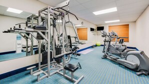 Une salle de sport équipée de matériel d’exercice, dotée d’un miroir et recouverte d’un tapis bleu.