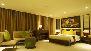 A hotel room with a bed, a sofa, a nightstand, a lamp, a painting, and a large window. - Villa Hue (Hue)