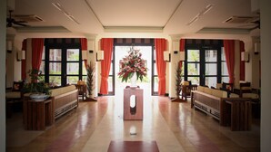 A hotel lobby with a central reception desk, red curtains, and potted plants. - Villa Hue (Hue)