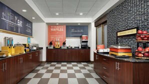 A modern kitchen area with a checkered floor, wooden cabinets, and a waffle station.