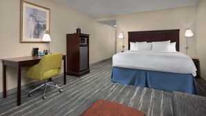 A hotel room with a bed, desk, chair, and a television.