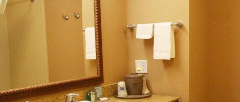 A bathroom with a sink, mirror, towel rack, and a trash bin.