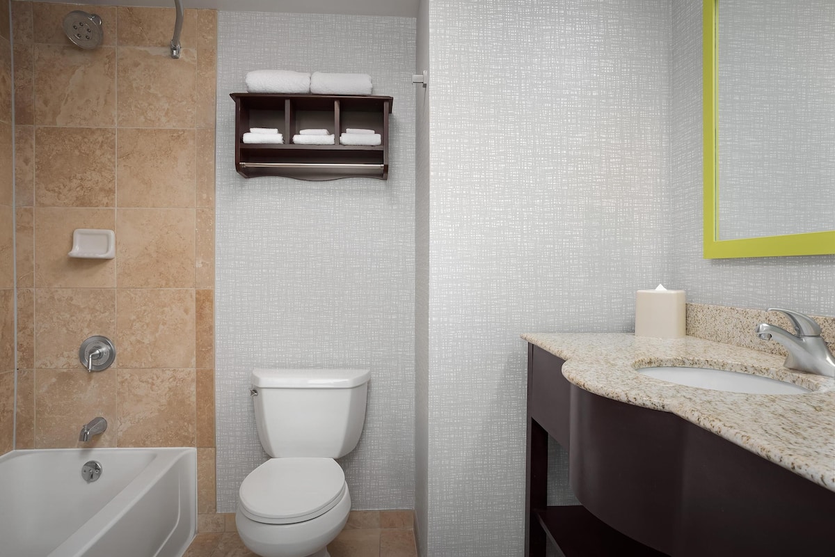 A modern bathroom with a bathtub, toilet, and vanity with a sink.