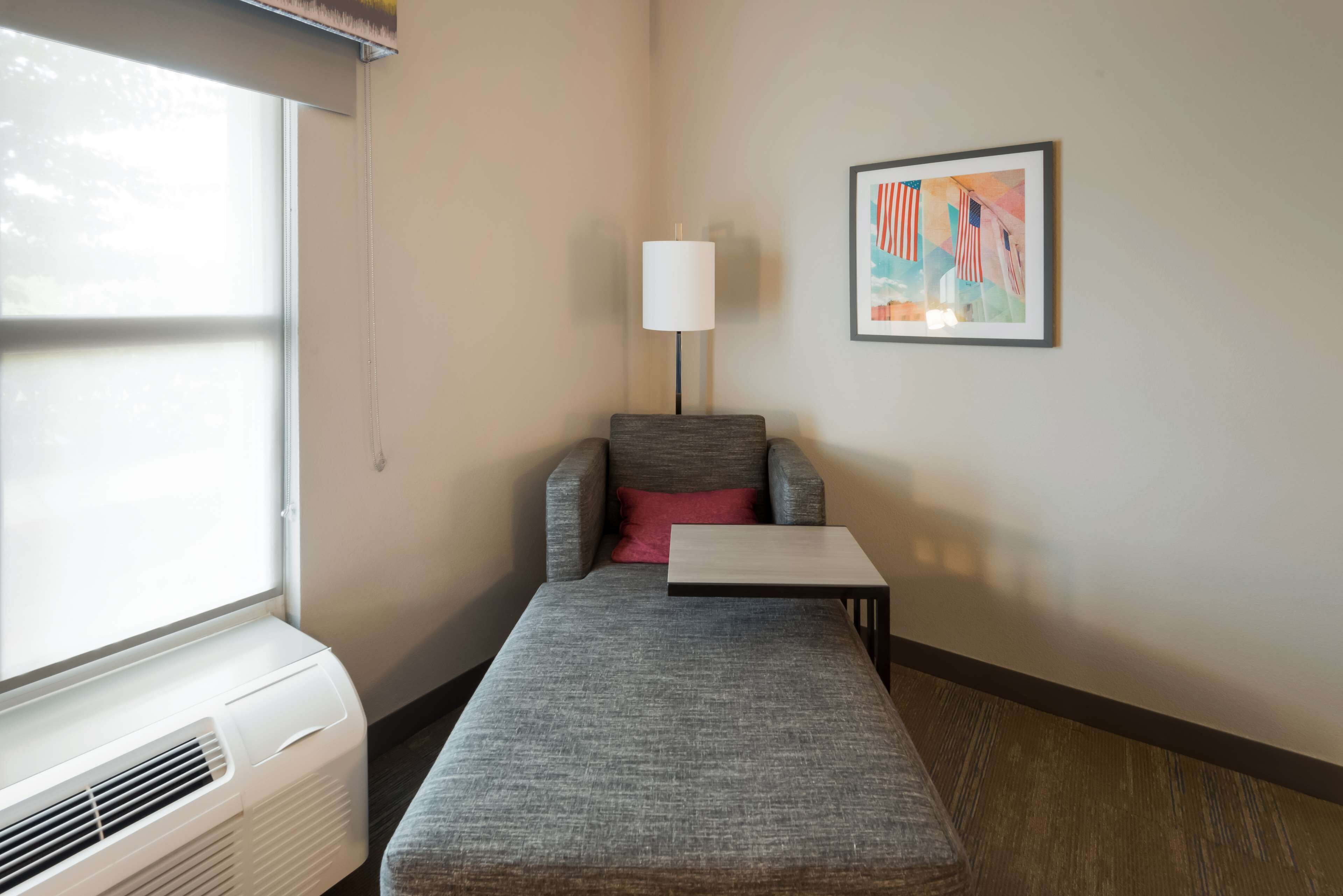 A compact room with a gray sofa, a small table, a lamp, and a window.