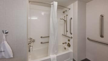 A modern bathroom with a walk-in shower, grab bars, and a towel rack.