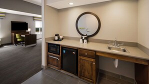 A modern hotel bathroom with a sink, mirror, and a coffee maker.
