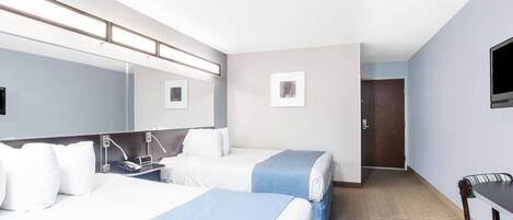 Una habitación de hotel con dos camas, un escritorio, una silla, un televisor y una puerta.