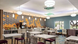 Um restaurante moderno com parede de padrão geométrico, várias mesas e cadeiras, e um espaço de bar.