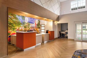 A hotel reception area with a large mural, wooden reception desks, and a spacious interior. - La Quinta Inn & Suites by Wyndham San Antonio N Stone Oak (San Antonio)