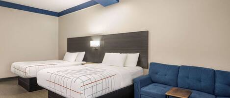 Una habitación de hotel con dos camas, un sofá azul y una pequeña mesa.
