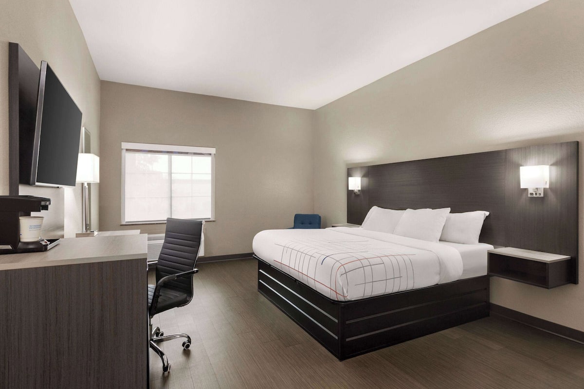 Une chambre d’hôtel équipée d’un lit, d’un bureau, d’une chaise et d’un téléviseur fixé au mur.