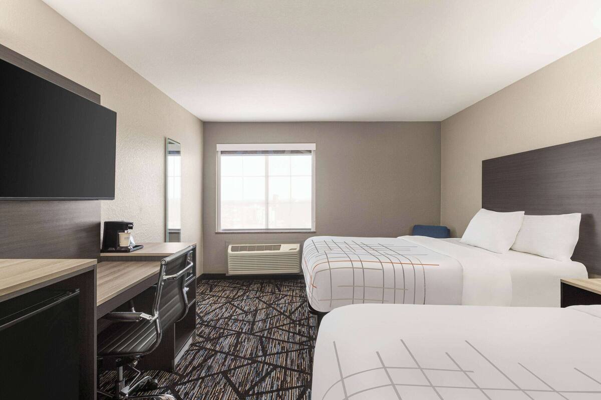 Une chambre d’hôtel avec un lit, un bureau, une chaise, une télévision et une fenêtre.