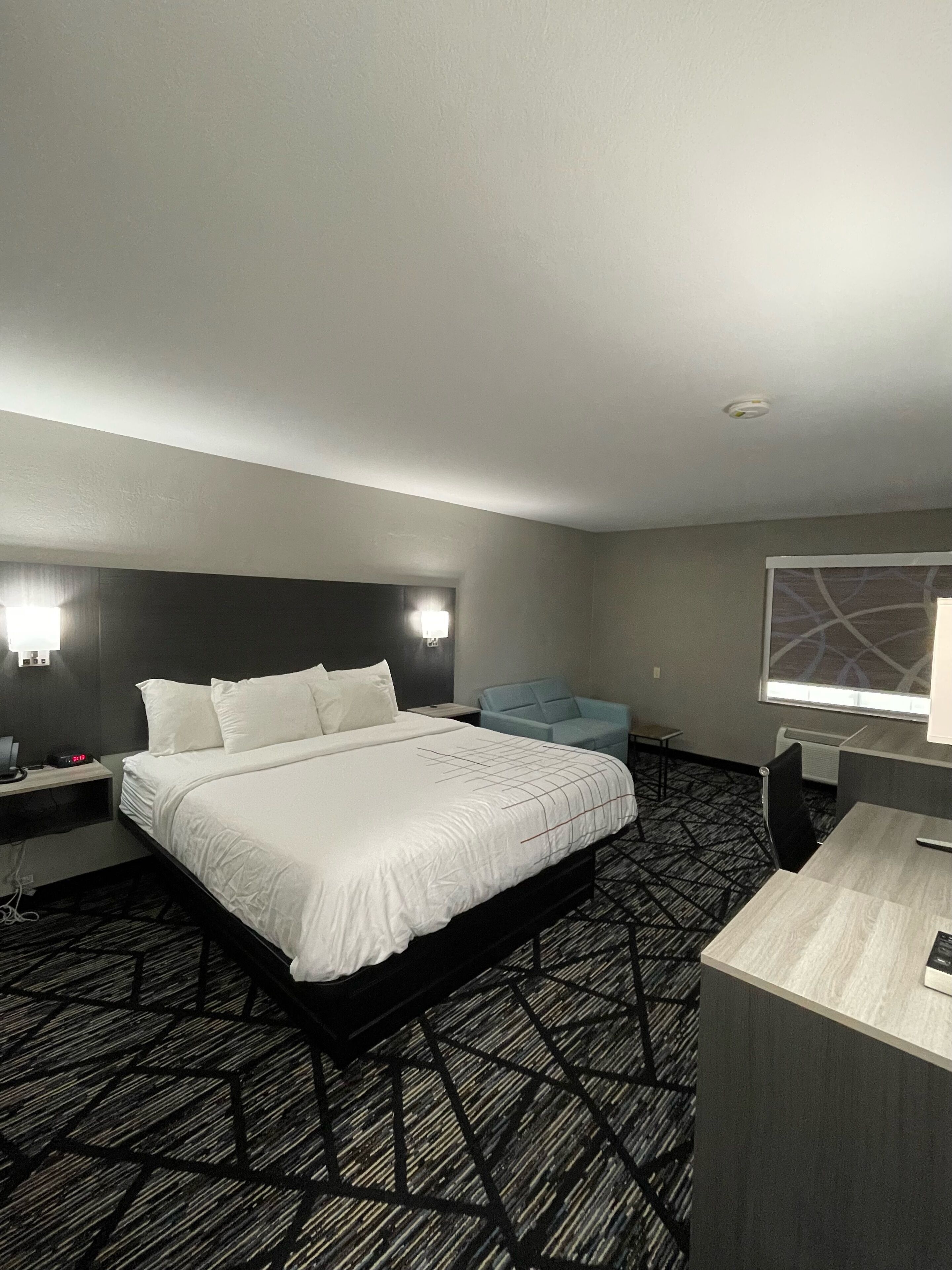 A hotel room with a large bed, a desk, a chair, and a window with a view.